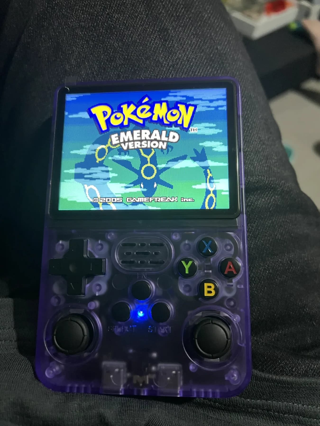 Playing Pokémon Emerald on a purple handheld console