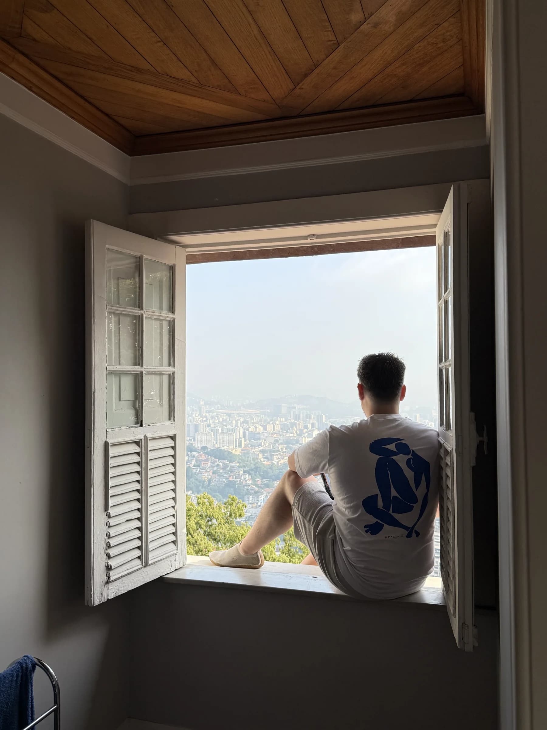 Adrià Tormo sitting in an open window overlooking Rio de Janeiro